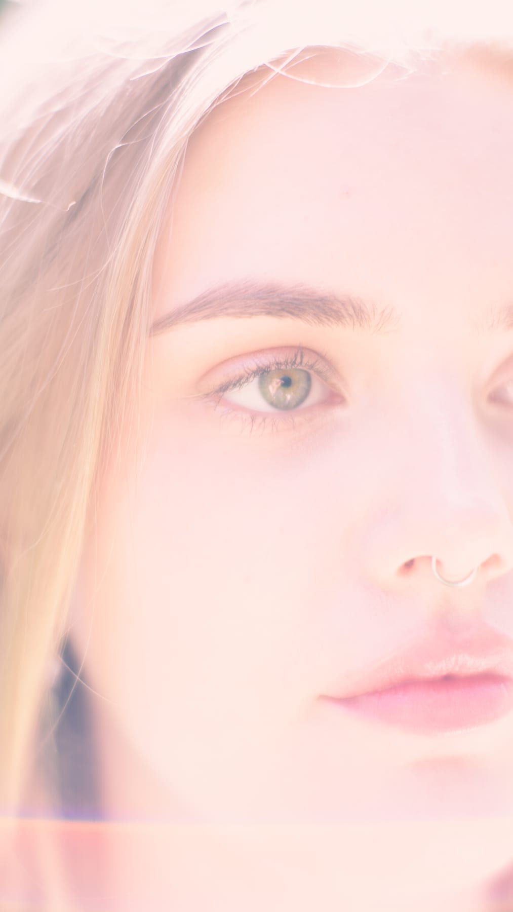 Soft, pale close-up of a woman's face with light eyes.