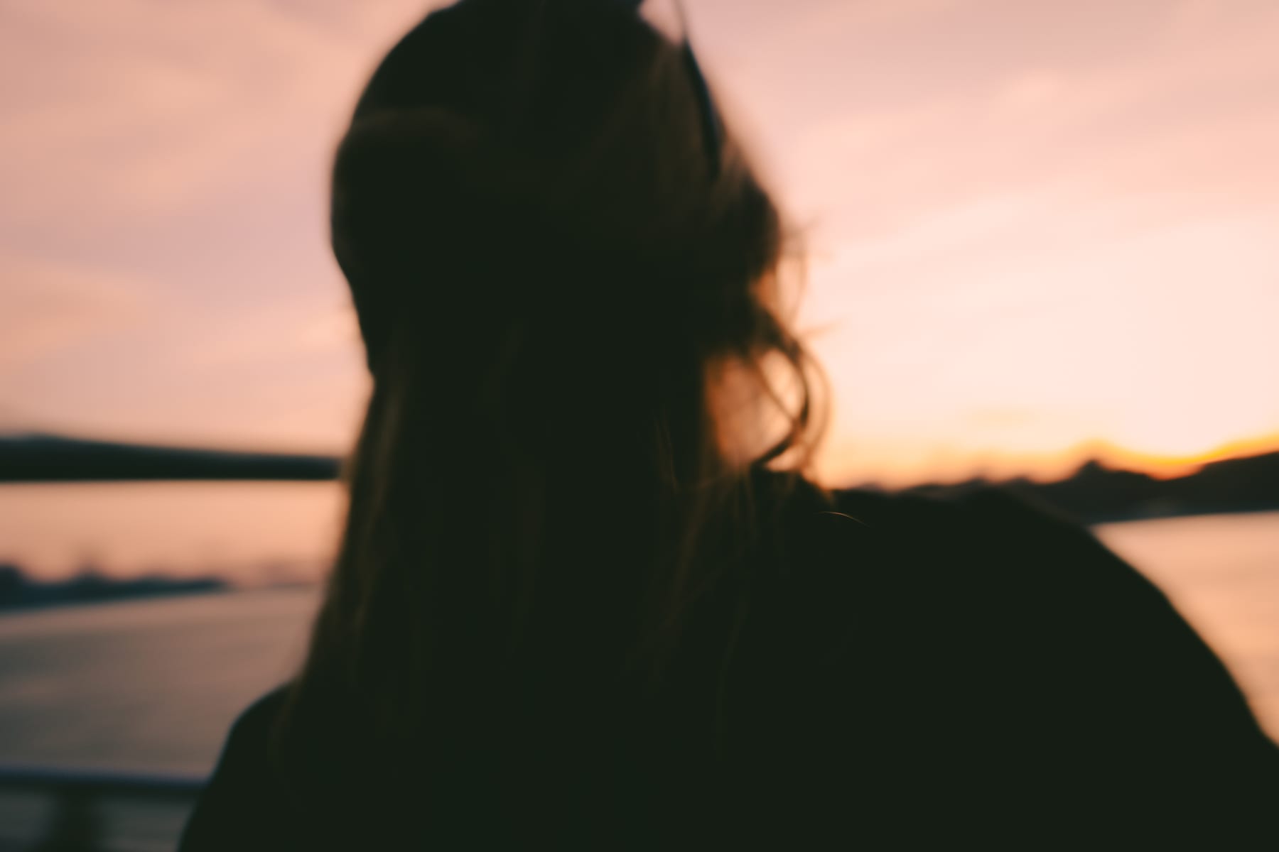 Silhouette of a long-haired woman by the East River at sunset, New York.